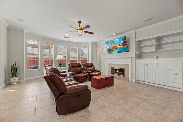 tiled living room with a tiled fireplace, ceiling fan, and ornamental molding