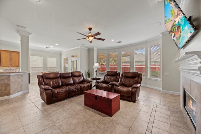 living room featuring a tile fireplace, ornate columns, and ornamental molding