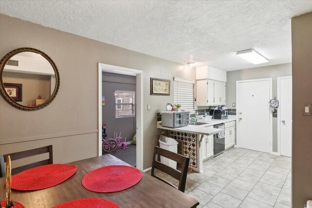 kitchen with black dishwasher, sink, white cabinetry, and a textured ceiling