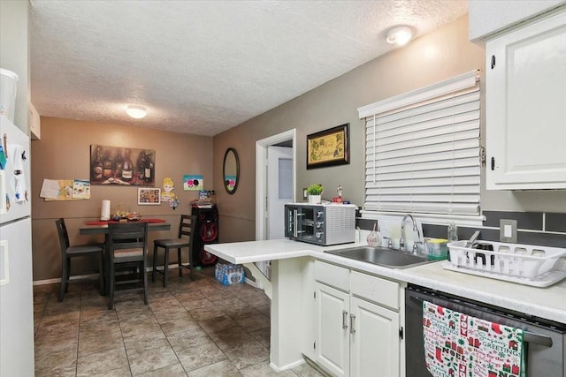 kitchen featuring dishwasher, sink, white cabinetry, and a textured ceiling