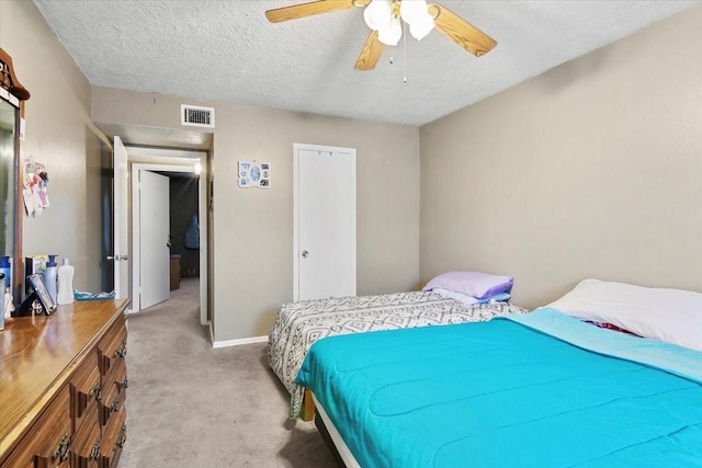 carpeted bedroom with ceiling fan and a textured ceiling