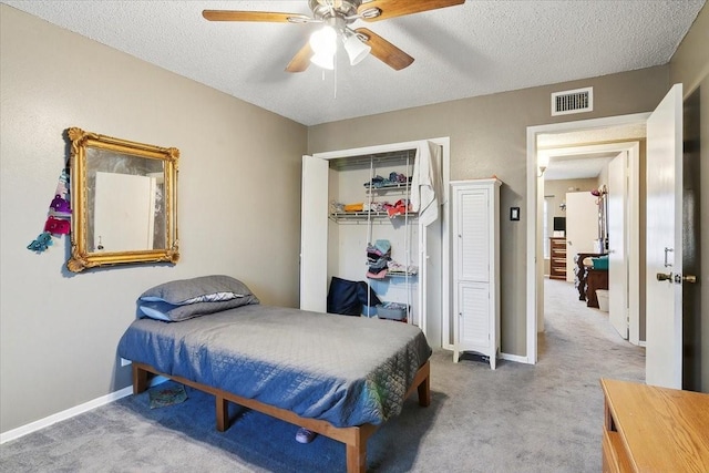 bedroom featuring a textured ceiling, ceiling fan, carpet, and a closet