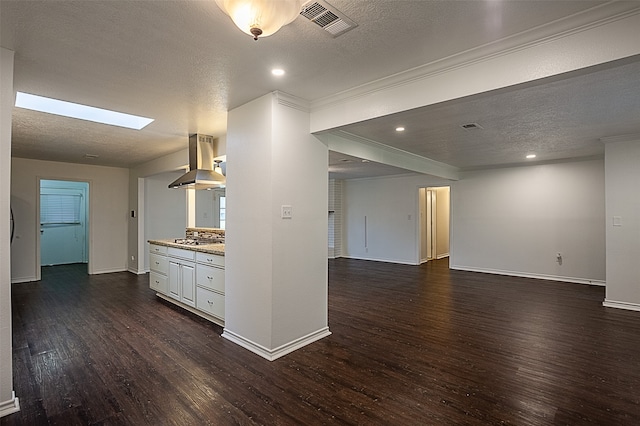 interior space with a skylight, dark hardwood / wood-style flooring, crown molding, and a textured ceiling