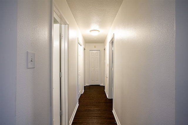 hall with dark wood-type flooring and a textured ceiling