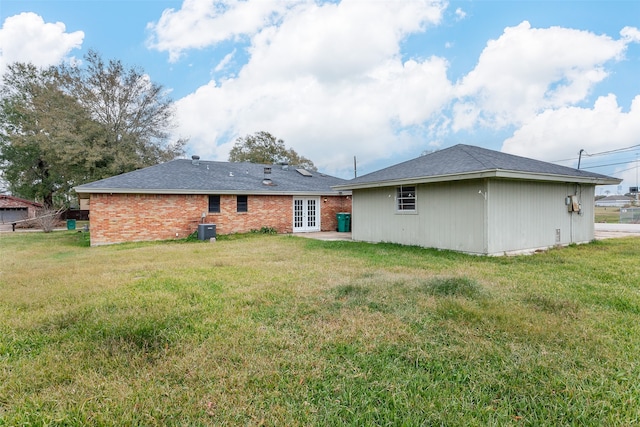 rear view of house with a lawn, central AC unit, and french doors