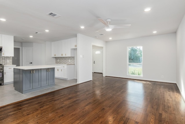 kitchen featuring gray cabinets, white cabinetry, a kitchen island, decorative backsplash, and light wood-type flooring