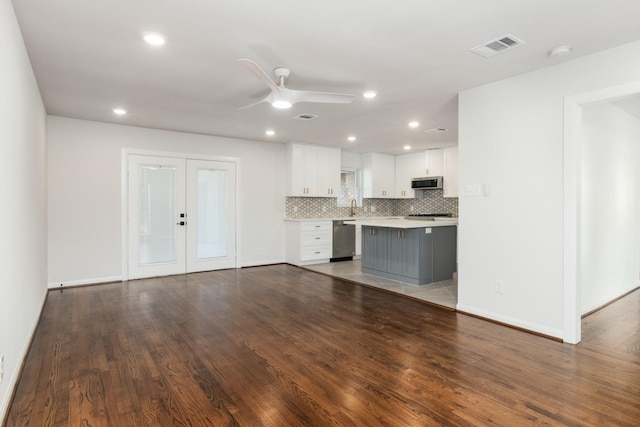 kitchen with appliances with stainless steel finishes, dark hardwood / wood-style floors, white cabinets, decorative backsplash, and french doors