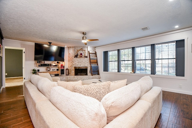 living room with ceiling fan, a fireplace, and a textured ceiling