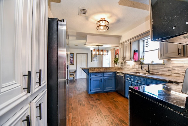 kitchen with sink, blue cabinetry, appliances with stainless steel finishes, backsplash, and kitchen peninsula