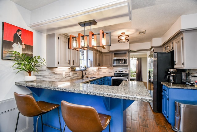 kitchen featuring sink, a breakfast bar area, backsplash, stainless steel appliances, and kitchen peninsula