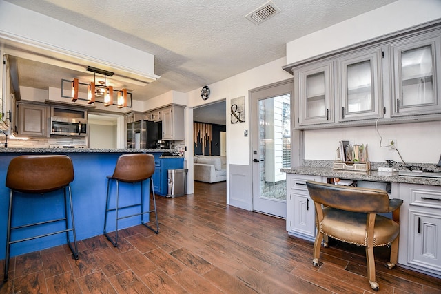 kitchen featuring dark wood-type flooring, an inviting chandelier, a kitchen bar, black fridge with ice dispenser, and decorative light fixtures