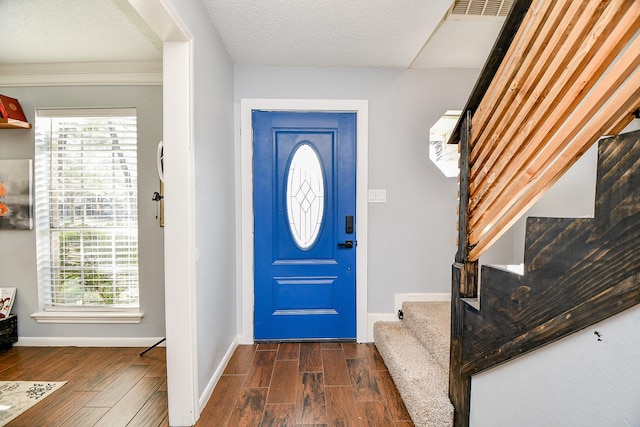 entryway featuring dark hardwood / wood-style flooring, ornamental molding, and a textured ceiling