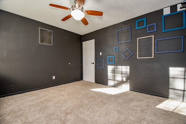 empty room featuring a textured ceiling, light colored carpet, and ceiling fan