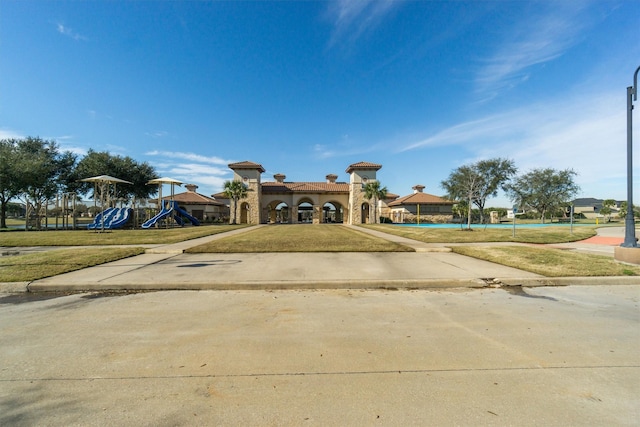 mediterranean / spanish-style house featuring a front lawn, playground community, and concrete driveway