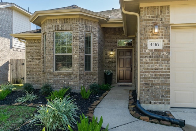 property entrance with a garage, brick siding, and fence