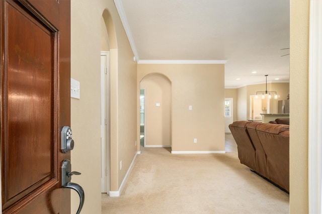 hall featuring light carpet, an inviting chandelier, and crown molding