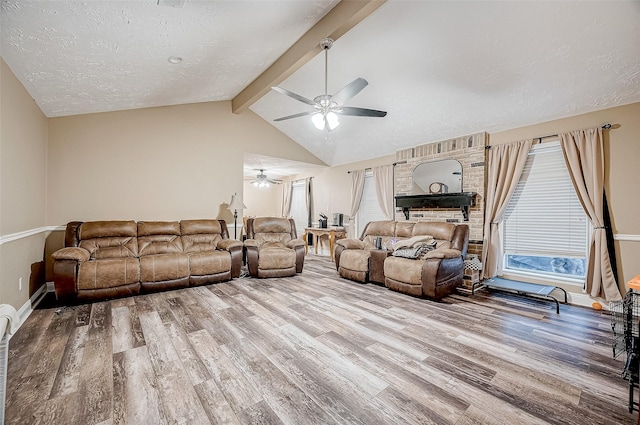 living room featuring ceiling fan, vaulted ceiling with beams, a textured ceiling, and hardwood / wood-style flooring