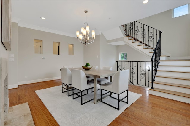 dining area with a chandelier, crown molding, and light hardwood / wood-style flooring