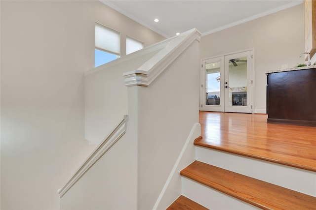 staircase featuring hardwood / wood-style flooring, crown molding, a healthy amount of sunlight, and french doors