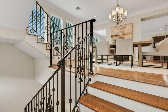 staircase featuring crown molding and an inviting chandelier