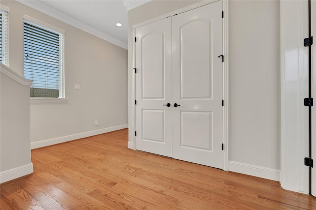 unfurnished bedroom with a closet, crown molding, and light hardwood / wood-style flooring