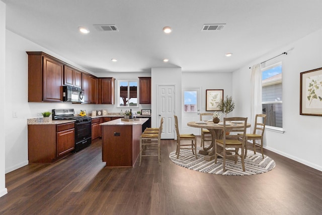 kitchen featuring a kitchen breakfast bar, a kitchen island, dark hardwood / wood-style flooring, and black appliances