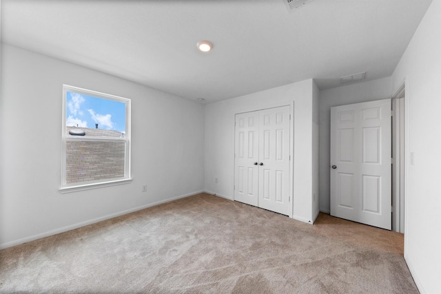 unfurnished bedroom with a closet and light carpet