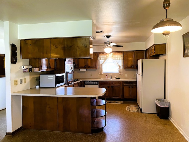 kitchen featuring ceiling fan, pendant lighting, kitchen peninsula, sink, and appliances with stainless steel finishes