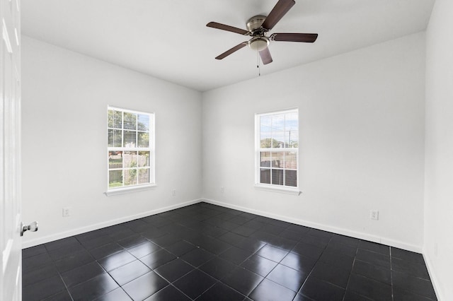 empty room with ceiling fan and dark tile patterned floors