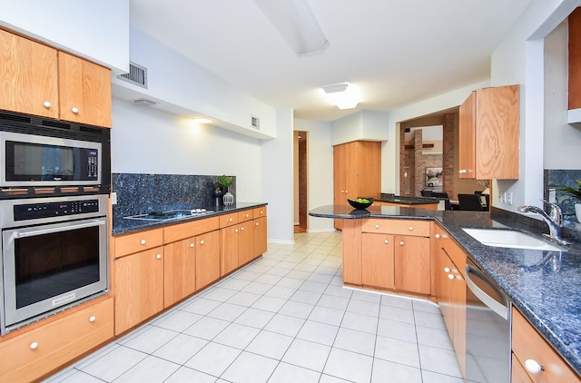 kitchen featuring stainless steel appliances, kitchen peninsula, dark stone counters, and sink