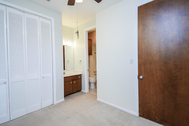 unfurnished bedroom featuring ceiling fan, light colored carpet, a closet, and connected bathroom