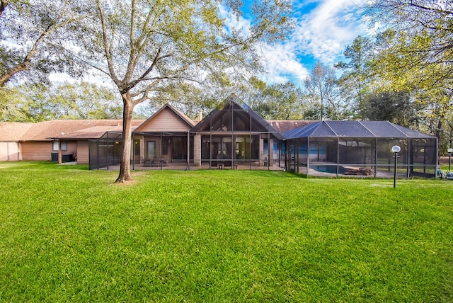 back of house featuring glass enclosure and a lawn