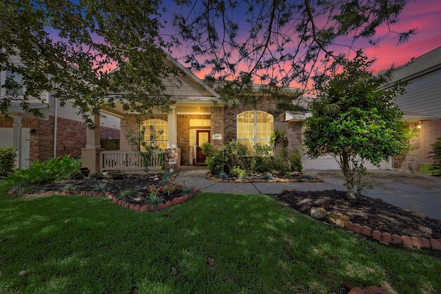 view of front of home featuring a lawn, a porch, and a garage