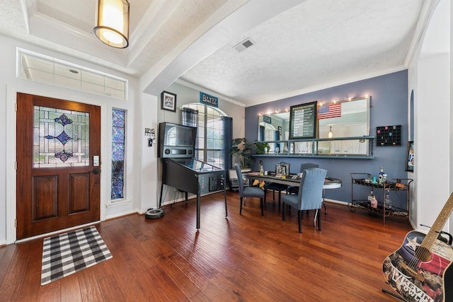 foyer entrance with crown molding, a textured ceiling, and hardwood / wood-style floors