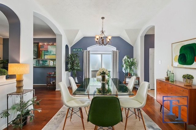 dining area featuring dark wood-type flooring, lofted ceiling, and an inviting chandelier