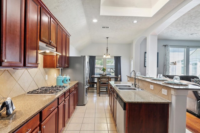 kitchen featuring light stone countertops, appliances with stainless steel finishes, lofted ceiling, and sink