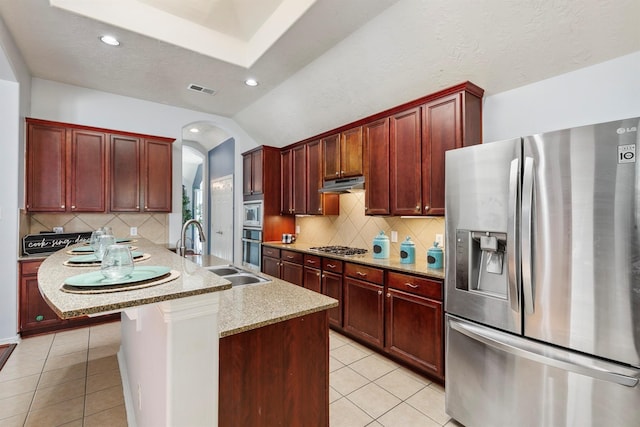 kitchen with light stone countertops, appliances with stainless steel finishes, sink, light tile patterned floors, and a breakfast bar area