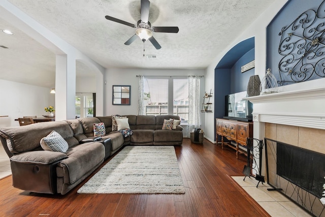 living room with ceiling fan, a fireplace, a textured ceiling, and hardwood / wood-style floors