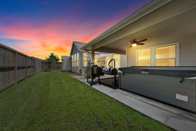 yard at dusk featuring ceiling fan and a patio area