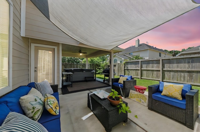 patio terrace at dusk featuring ceiling fan, an outdoor living space, and a hot tub