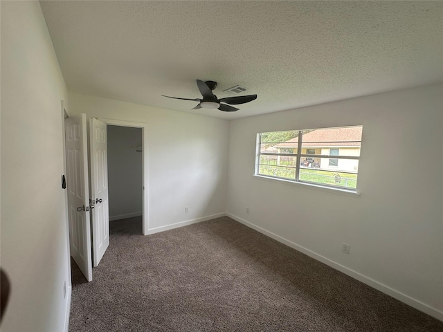 spare room with ceiling fan, dark carpet, and a textured ceiling