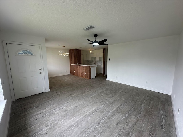 unfurnished living room featuring ceiling fan, a textured ceiling, and dark hardwood / wood-style flooring