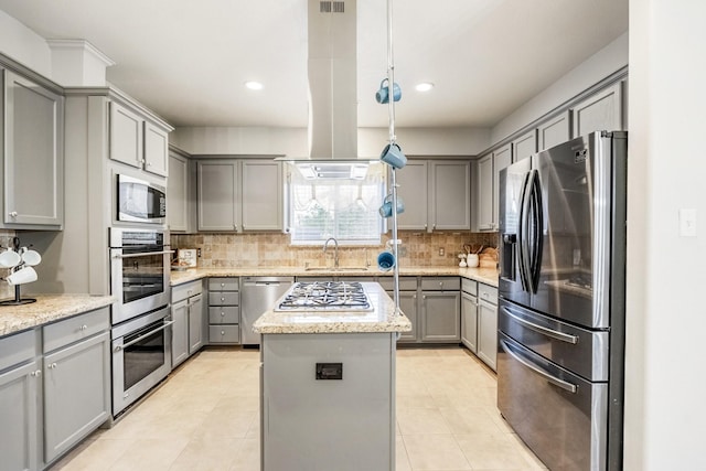 kitchen featuring appliances with stainless steel finishes, gray cabinetry, island range hood, and a kitchen island