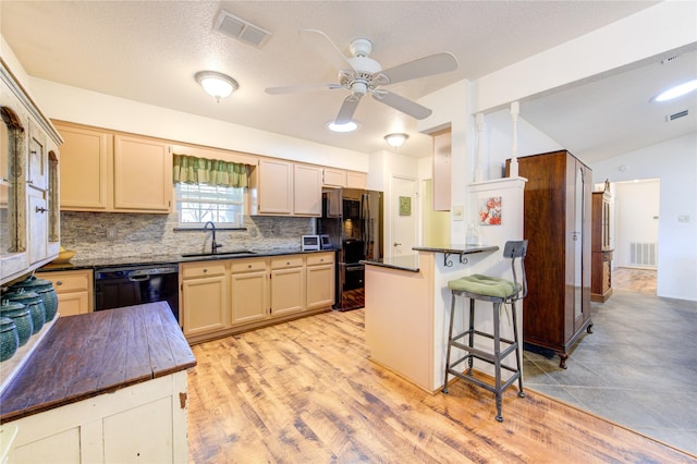 kitchen with kitchen peninsula, tasteful backsplash, sink, a breakfast bar, and black appliances