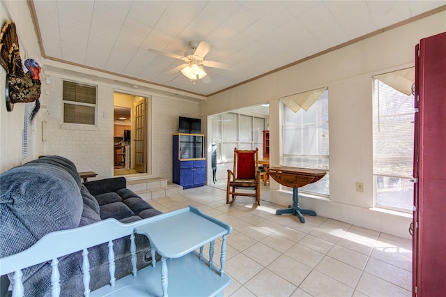 tiled living room with ceiling fan and crown molding