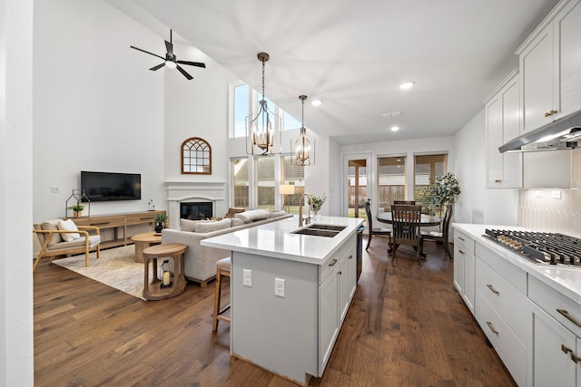 kitchen with a kitchen island with sink, sink, hanging light fixtures, and white cabinets