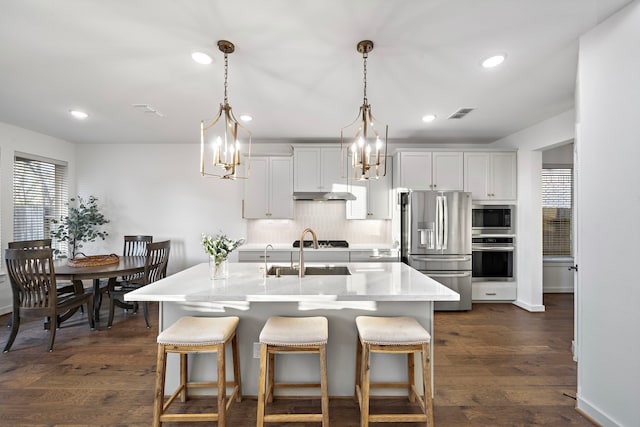 kitchen with stainless steel appliances, white cabinetry, dark hardwood / wood-style floors, and backsplash