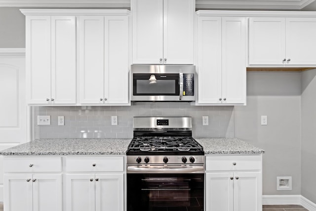 kitchen with tasteful backsplash, white cabinets, light stone counters, and stainless steel appliances