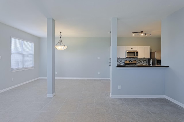 kitchen featuring decorative light fixtures, white cabinetry, stainless steel appliances, tasteful backsplash, and light tile patterned flooring