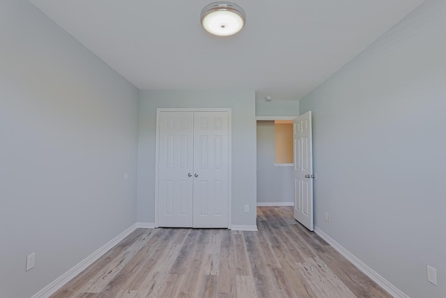 unfurnished bedroom with light wood-type flooring and a closet